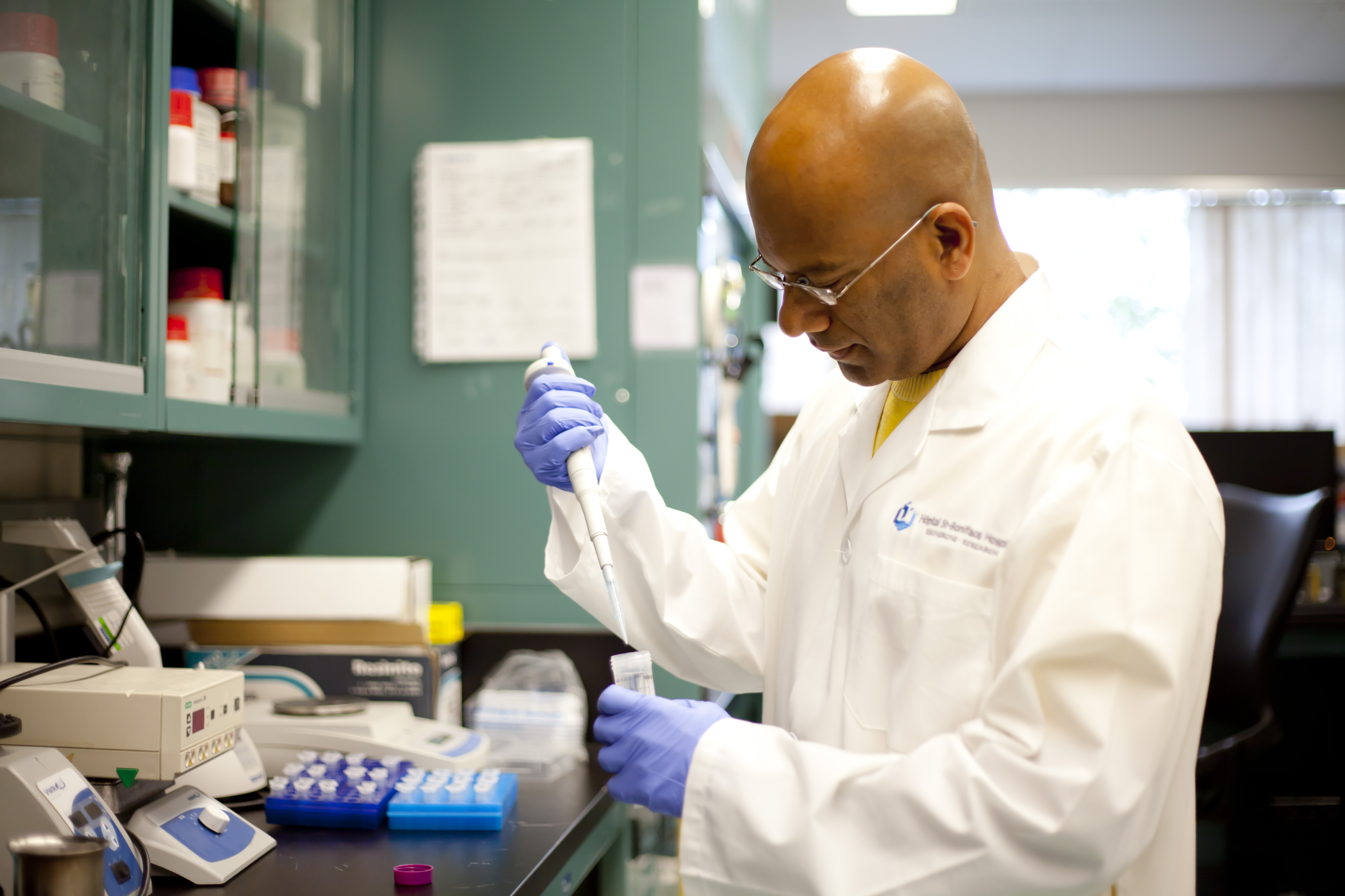 Photo of a researcher using a pipette to measure fluids in a lab